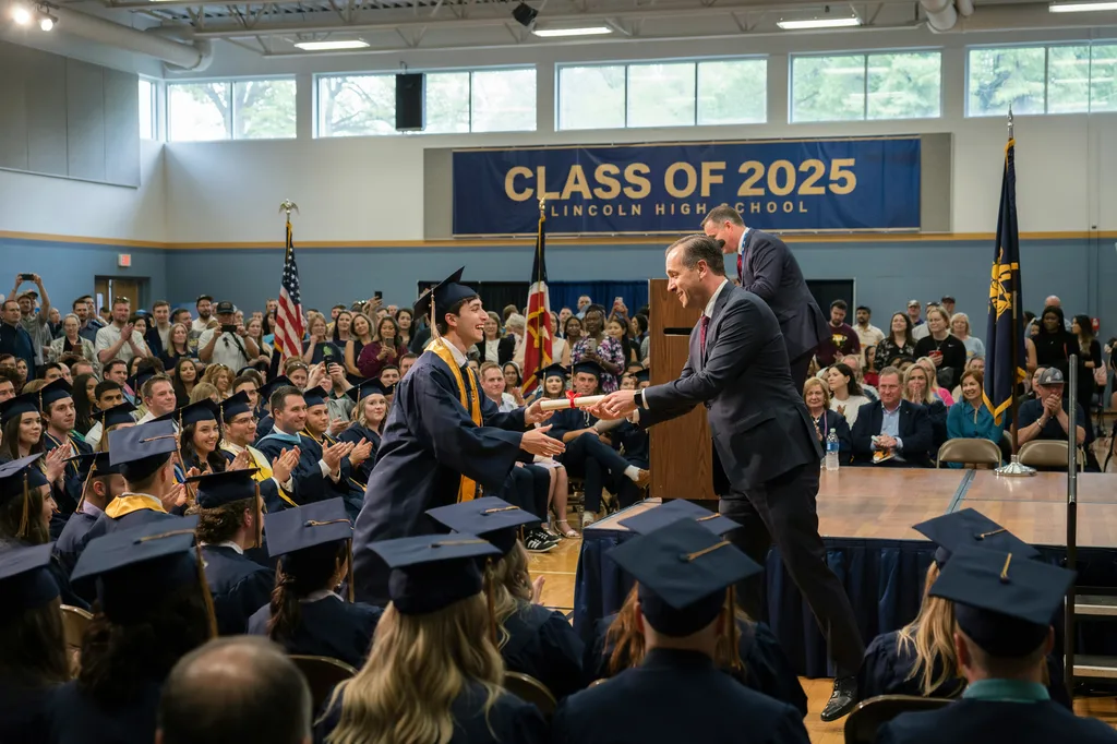 A graduate receiving their diploma at commencement.